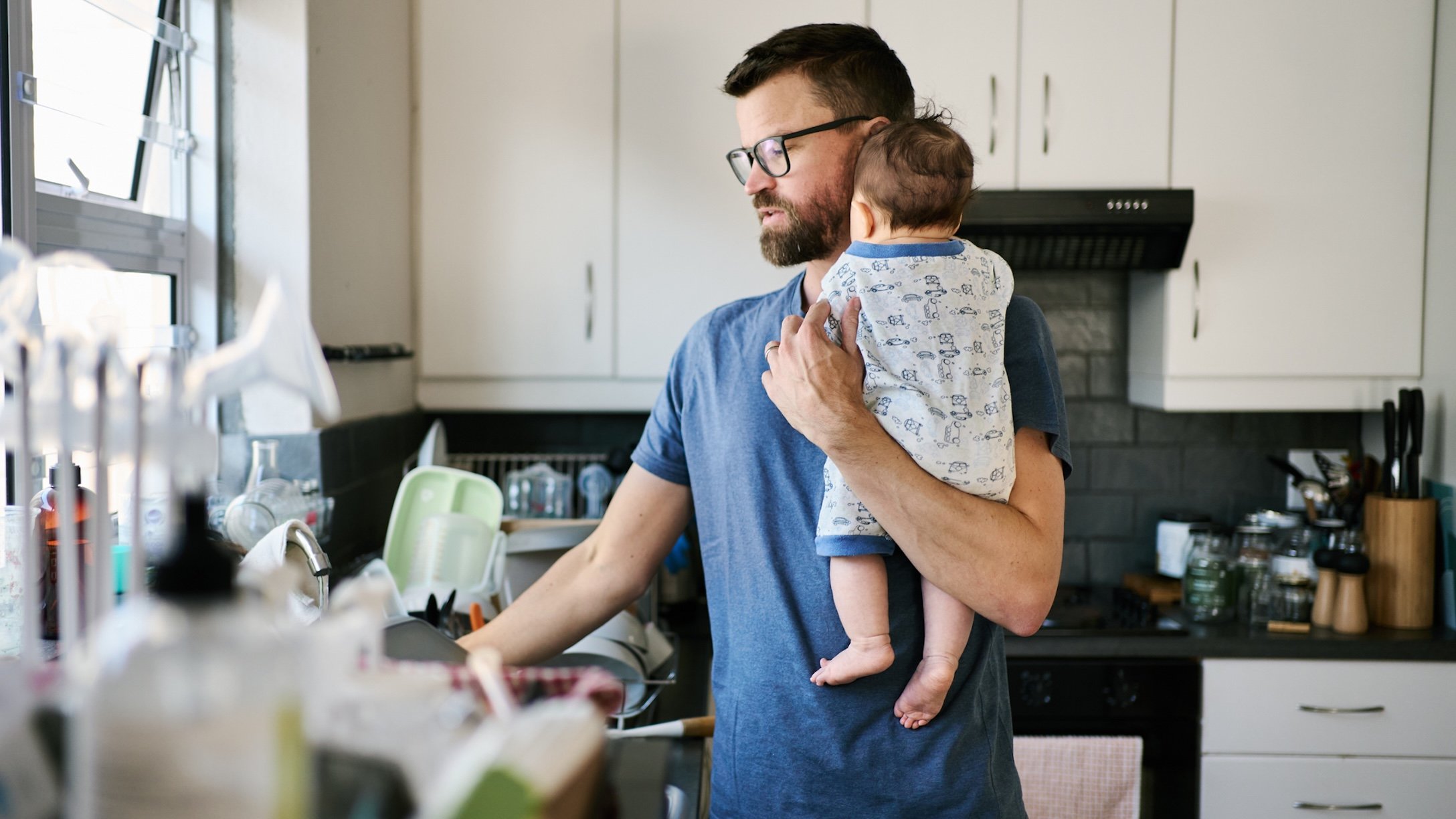 Dad busy at home with baby and chores.