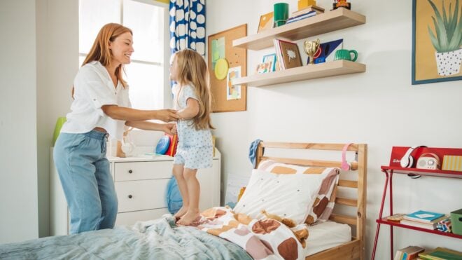 Mom plays with little girl in her bedroom
