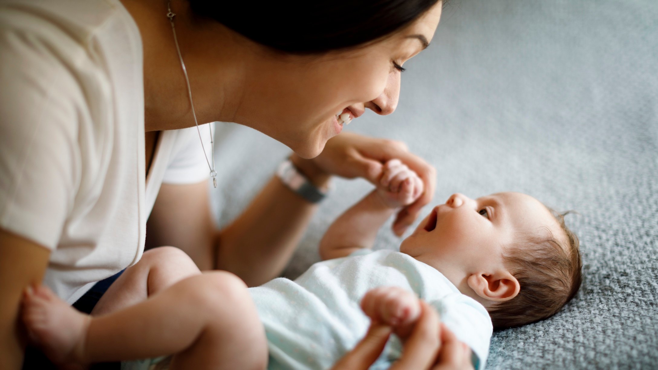 Mom talking to baby on bed
