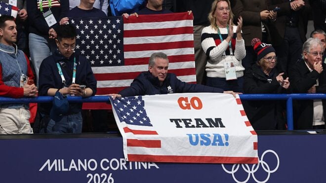 Man with gray hair holds sign at Olympics that says 'Go Team USA'