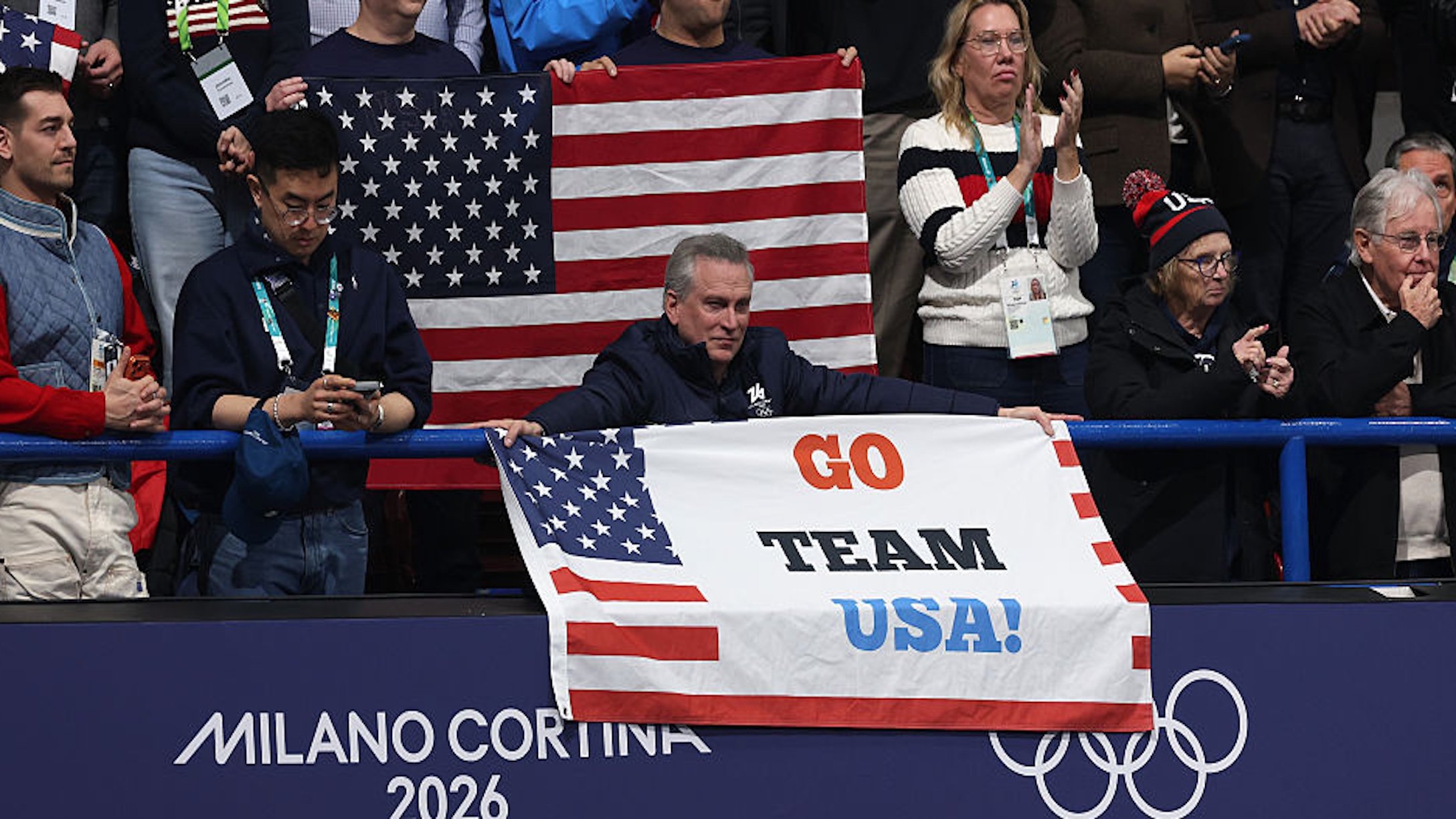 Man with gray hair holds sign at Olympics that says 'Go Team USA'