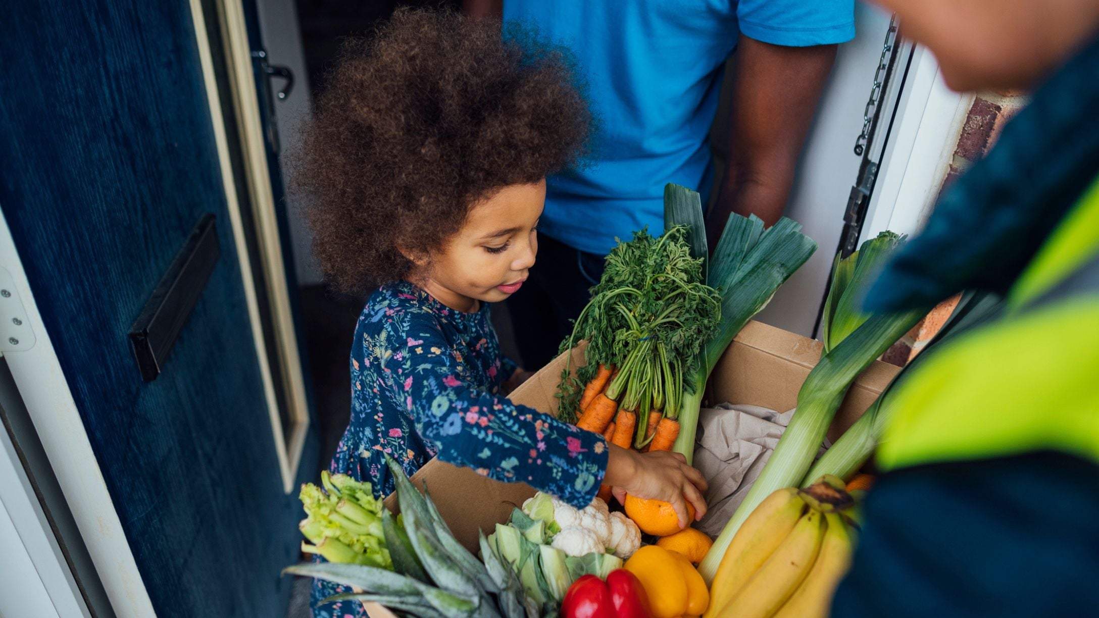 A young child going through a grocery delivery of food at their door