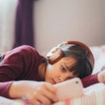 Kid in bed watching viral videos on smartphone