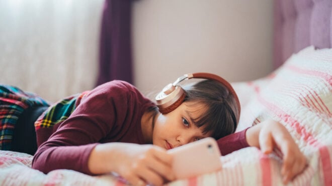 Kid in bed watching viral videos on smartphone