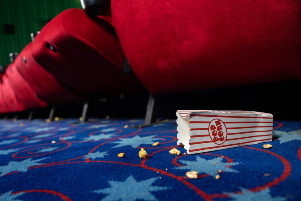 View of bucket of popcorn spilled on the movie theater floor
