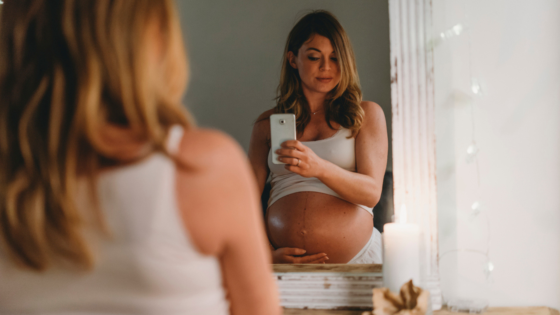pregnant woman taking selfie in the mirror