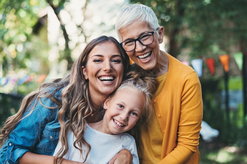 Portrait of happy grandmother, mother and daughter in the back yard