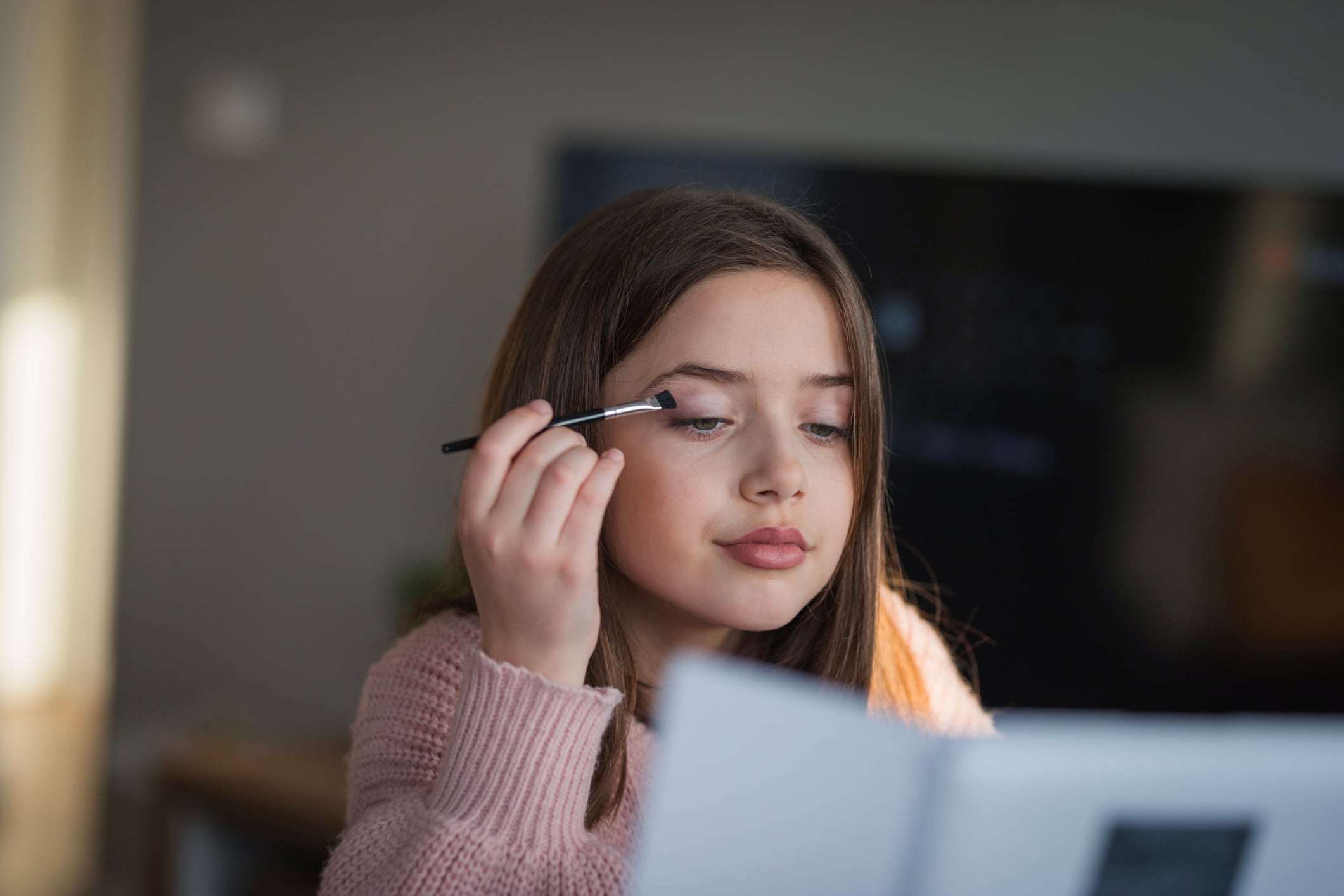 Young girl applying eye shadow seriously