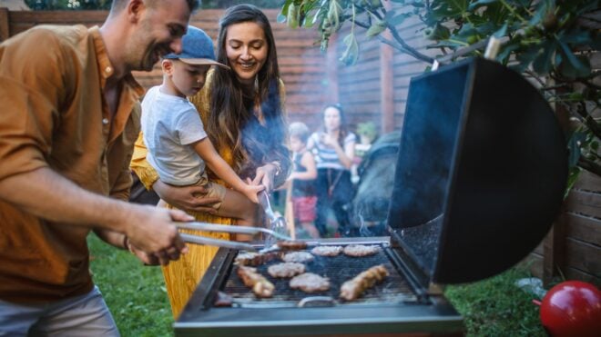 A man barbecuing with a woman and her child nearby