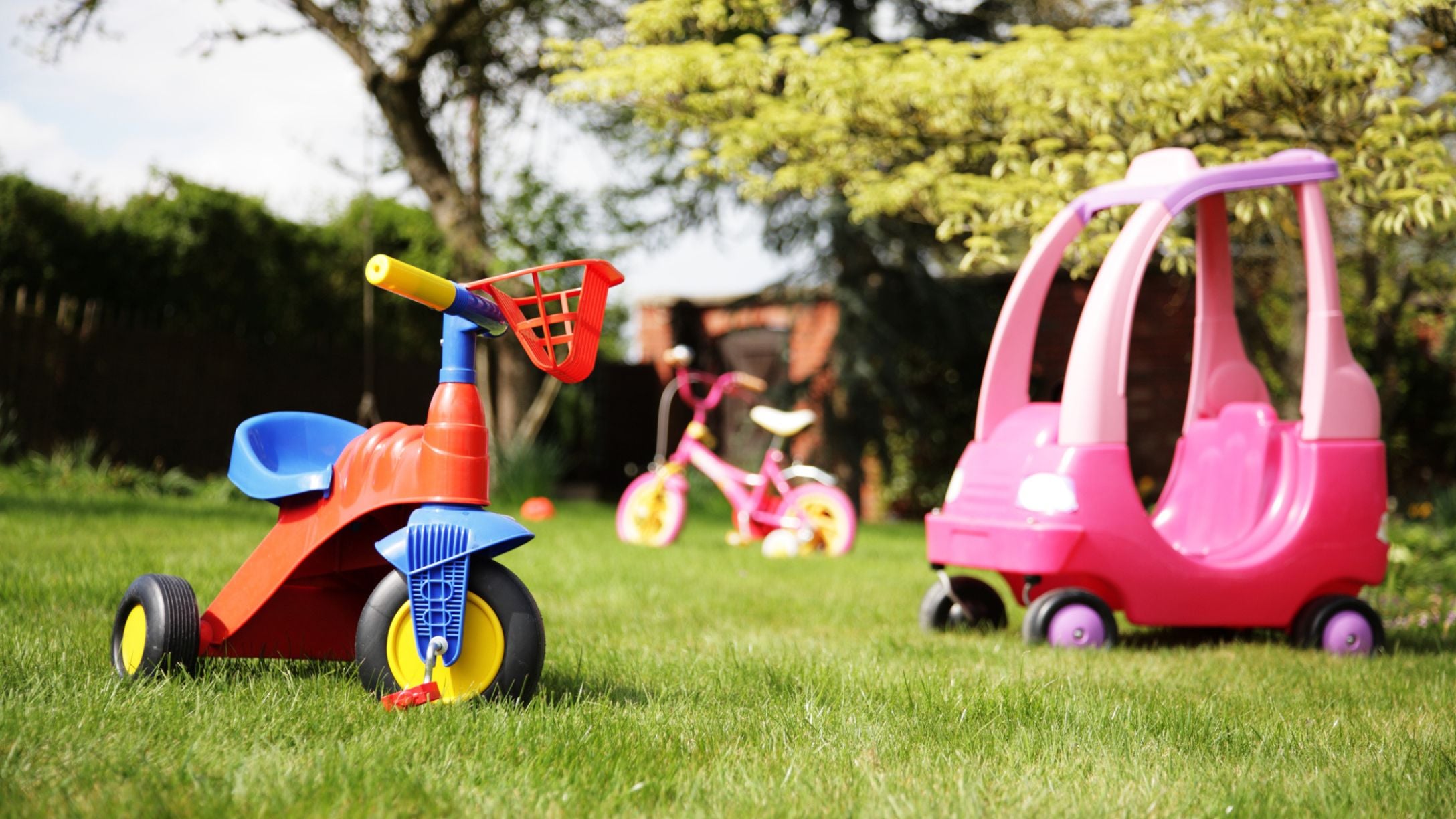 A variety of outdoor toys and bikes out in a yard