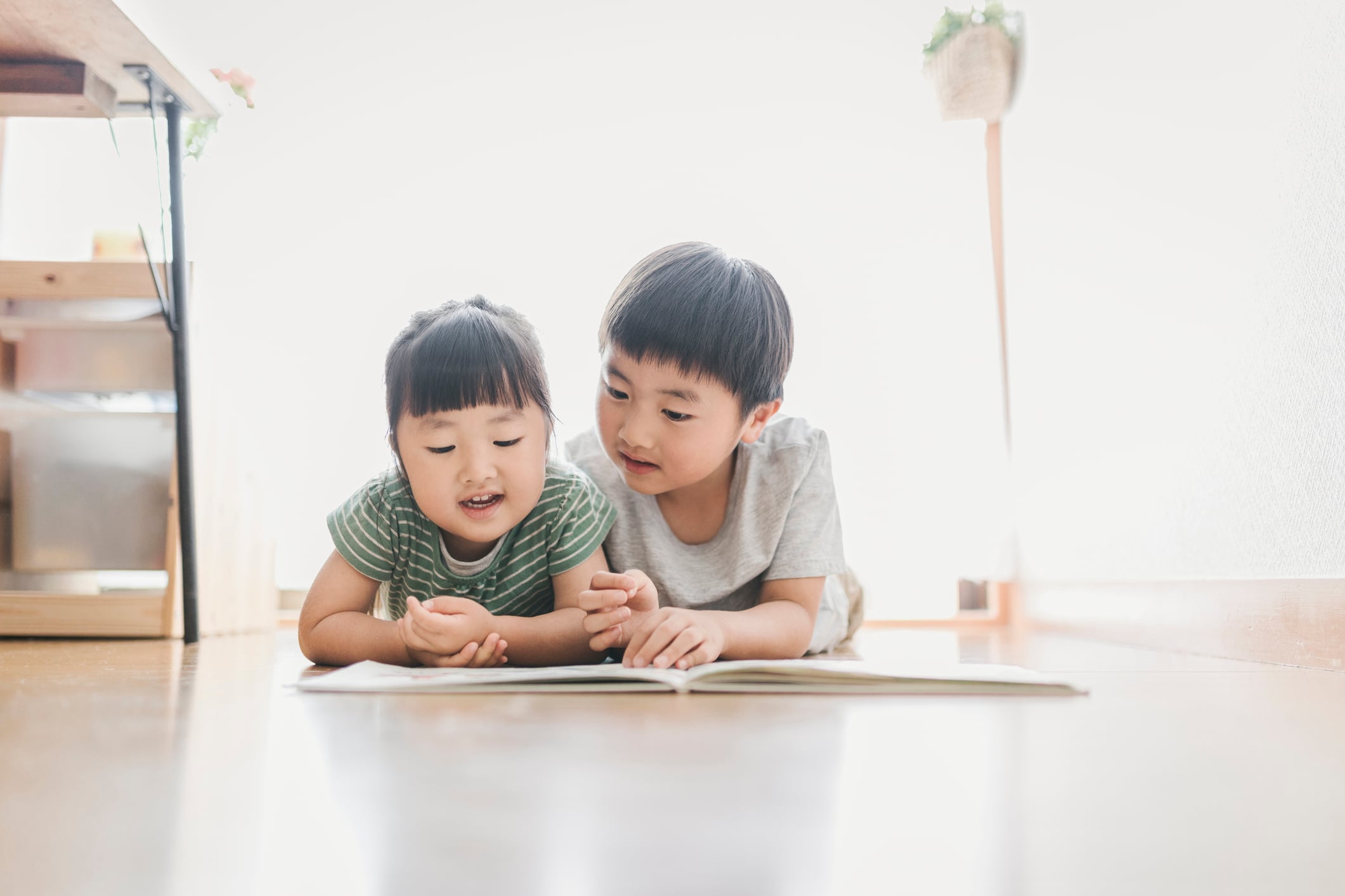 brother and sister reading a picture book in the living room.